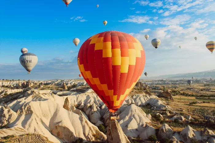 Colorful hot air balloons fly and float over a desert landscape